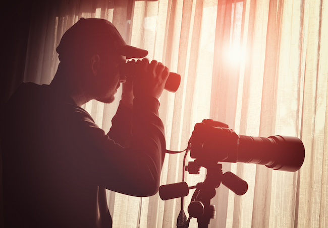 man with binoculars and camera control someone