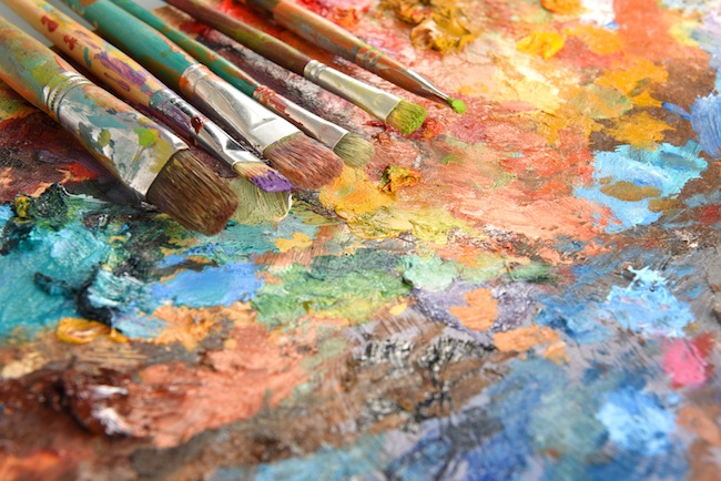 Artist paintbrushes over palette with oil colors