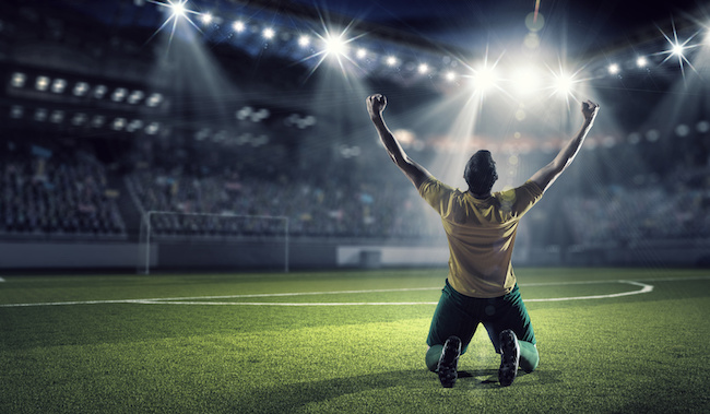 Soccer player celebrating victory while holding win cup